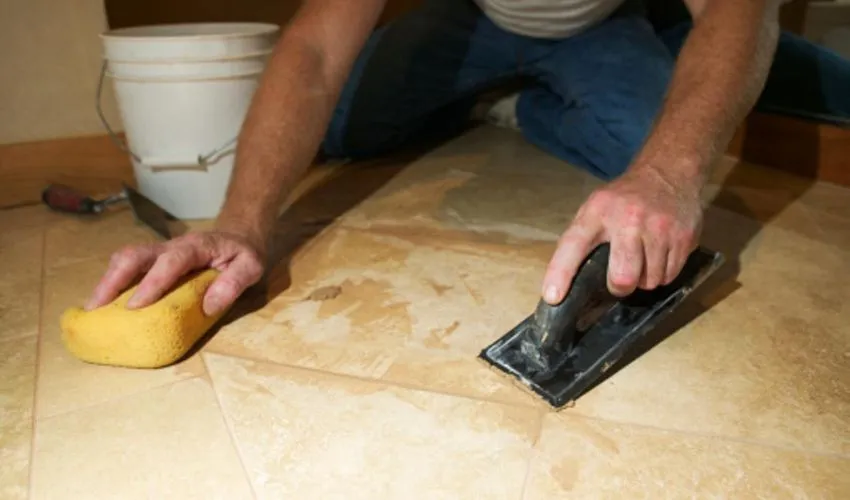 Man scraping off spray paint from floor surface with scraper tool