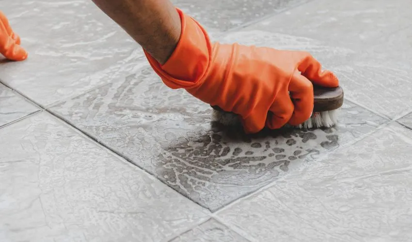 A Man Trying To Remove Spray Paint From Floor Using Brush